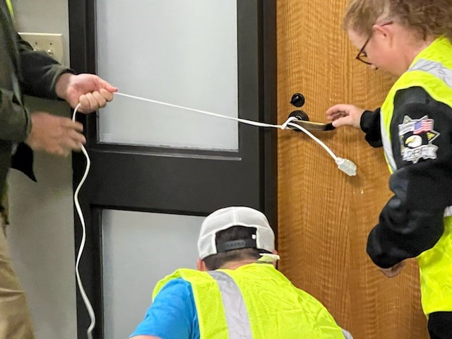 Participants use an extension cord to secure a door handle as part of an active threat exercise during the Run. Hide. Fight. course.